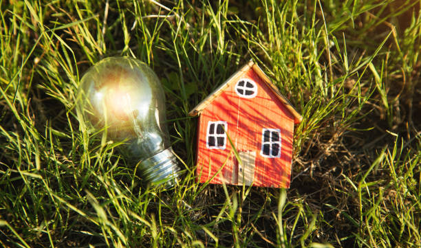 istock Lightbulb and house model on a background of green grass. 1397911662