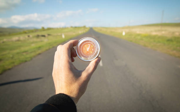 istock Traveler holding compass in road background. 1397911916