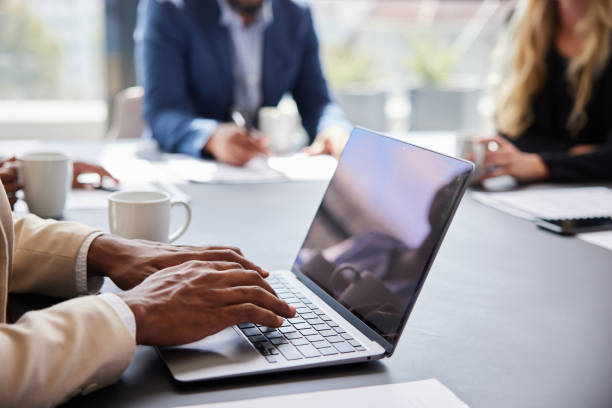 Young businessman working on a laptop during a boardroom meeting with coworkers stock photo
