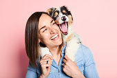 Handsome female with her Australian Berger puppy on studio pink