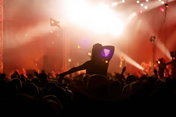 Photo of Men and women with raised hands at a concert event.