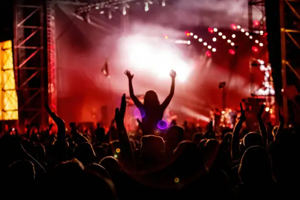 Photo of Men and women with raised hands at a concert event.