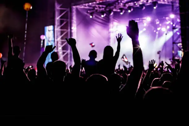 Photo of Men and women with raised hands at a concert event.