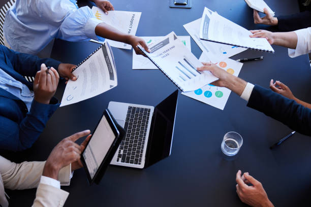 Businesspeople passing around graphs and charts during an office meeting stock photo