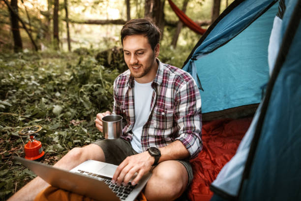 istock Young handsome man having a coffee while working from his camp in a forest 1397915093