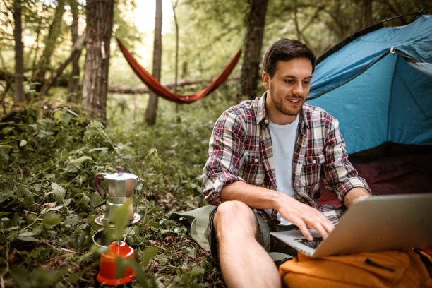 istock Young man working from his camp at forest, preparing coffee on a gas tank stove 1397915098