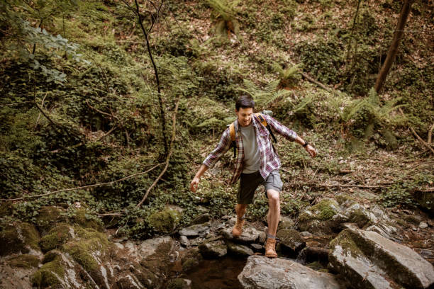 istock Young casually clothed hiker crossing small river 1397916297