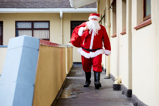 White male Santa clause in costume walking along a corridor