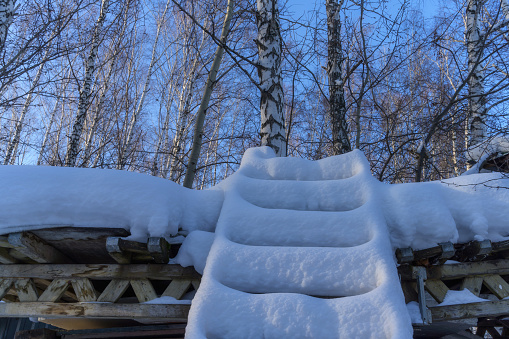 Stack of wooden logs covered with fresh snow on white background (cut out).