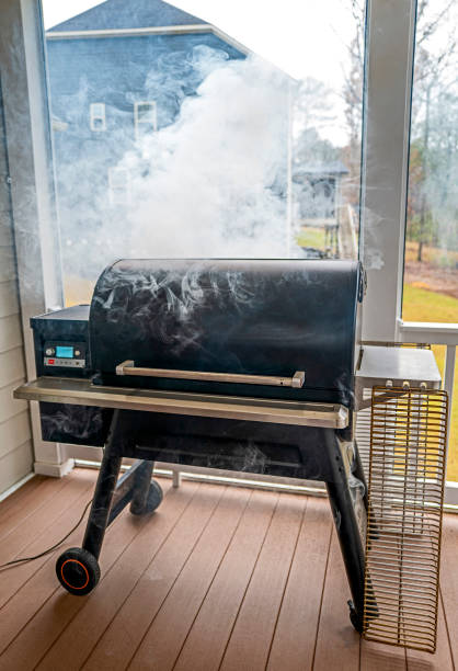 Un fumador de barbacoa en un porche que emite humo - foto de stock