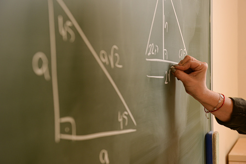 Teacher teaches math lesson on chalkboard