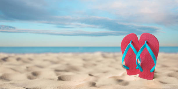 istock Pink flip flops on sandy beach near sea, space for text. Banner design 1397924531