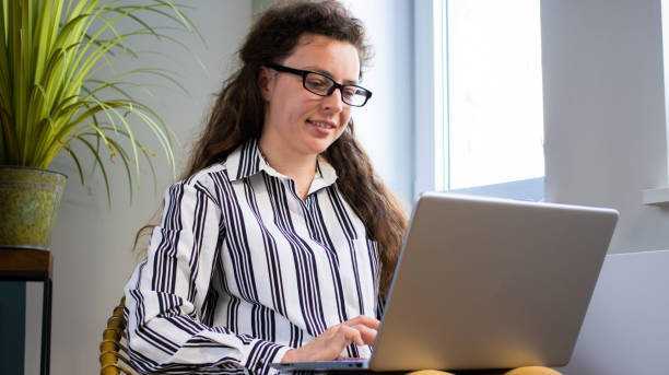 designer de mulheres grapic bem sucedidas assistindo tutorial sobre ideias criativas no computador portátil durante o processo de trabalho sentado no café. freelancer feliz com site de navegação de cabelo castanho usando internet 5g - grapic - fotografias e filmes do acervo