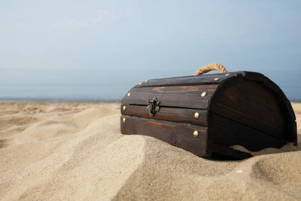 istock Closed wooden treasure chest on sandy beach, space for text 1397926336