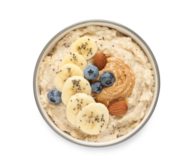 gustoso porridge di farina d'avena con diversi condimenti in ciotola su sfondo bianco, vista dall'alto - avena cereali da colazione foto e immagini stock