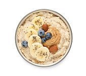Tasty oatmeal porridge with different toppings in bowl on white background, top view