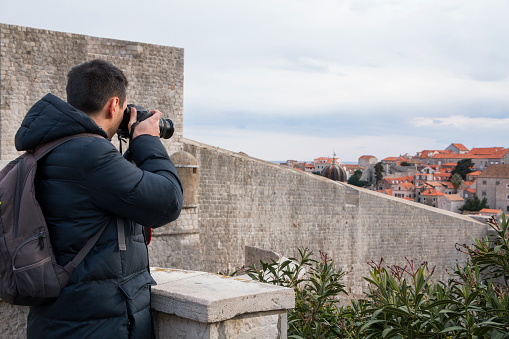 Tourist visiting the old town of Dubrovnik and photographing the panorama of the city.
