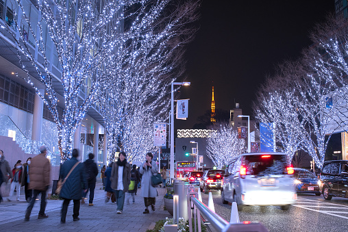 Tokyo, Japan - December 23, 2017: People walking on Roppongi Keyakizaka Street decorated with Christmas lights and Tokyo Tower.
