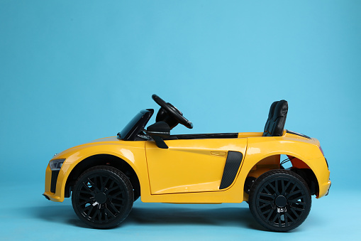 Child's electric toy car on light blue background