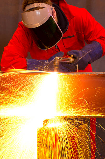 istock Welder bends to cut metal beam with orange sparks. 139793088