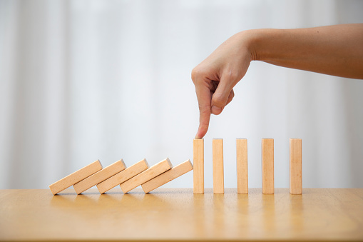 Falling pieces of dominoes on white background. Business, risk, management and finance concept