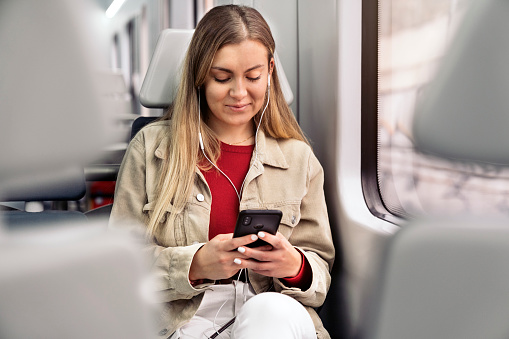 Stock photo of young attractive girl listening to music wearing headphones and looking at her phone.