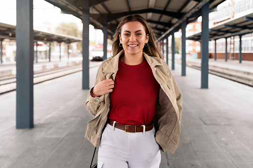 Stock photo of smiley girl looking at camera standing in a train platform.