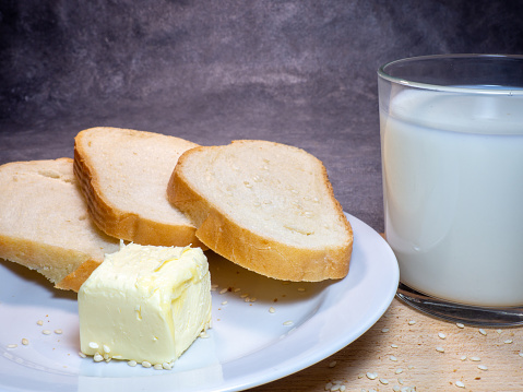 Pieces of rye and white bread with a glass of milk on a plate. Healthy breakfast. Bakery products with sesame seeds.