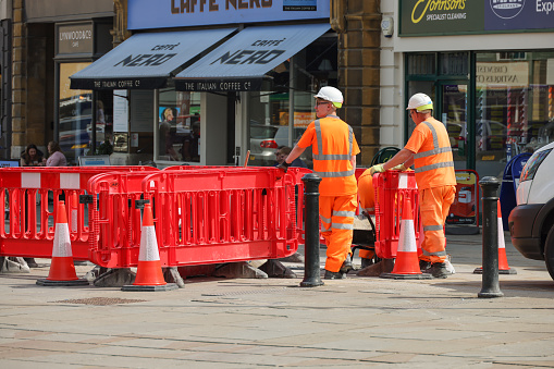 Workmen repairing the pavement and roads in the centre of the Cotswold market town of Cirencester in Gloucestershire