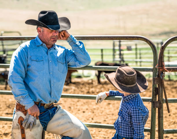 A man and boy talking as they take a break from work at a cattle ranch in the Western USA.
