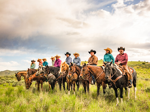 A large group of women and men together on horseback at a hill ranch in remote Utah, USA.