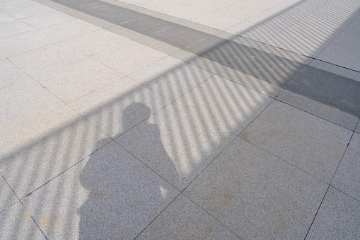 The shadows of people and railings are reflected on the stone slab