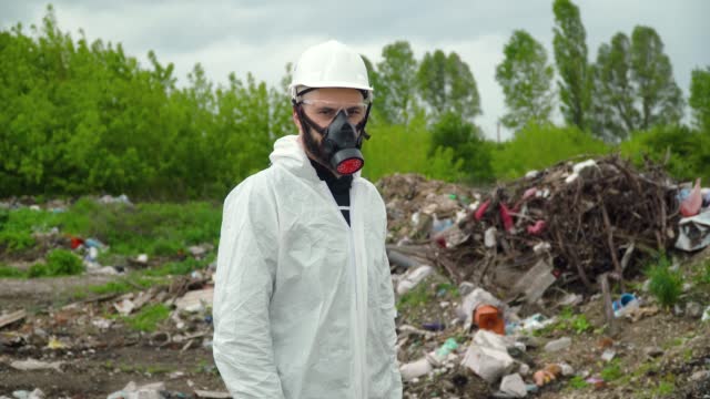 Activist scientist with respirator on landfill. Environmental pollution concept
