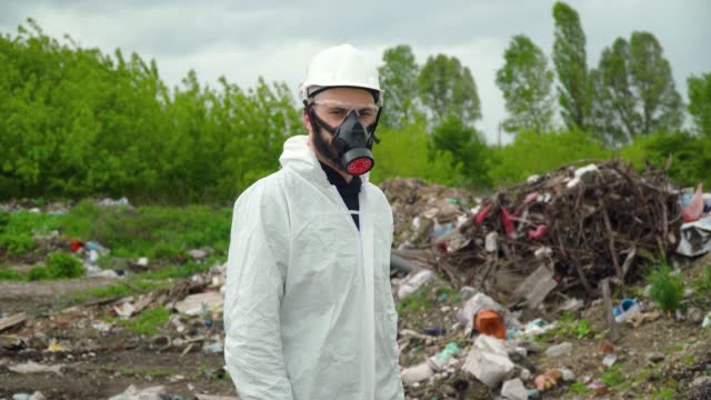 Activist scientist with respirator on landfill. Environmental pollution concept. Stop pollution