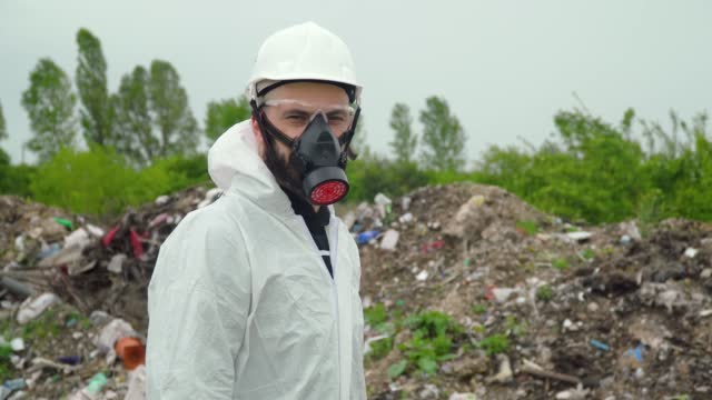 Activist scientist with protective mask on landfill. Environmental pollution concept