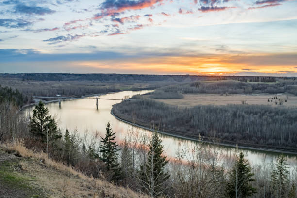 View to the Terwillegar Park Footbridge at sunset time with red sky reflection in the North saskatchewan river in early spring season