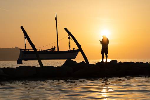 The silhouette of a fisherman. Early morning sunrise over water.