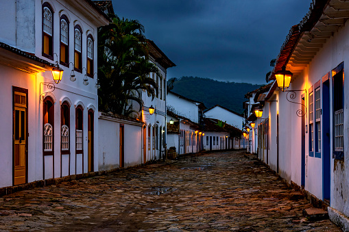 Streets and houses of the historic city of Paraty in the state of Rio de Janeiro illuminated at dusk with the mountains in the background