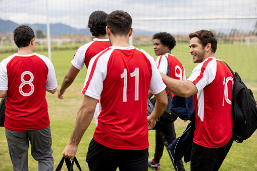 Rear view of a happy group of Latin American soccer players arriving at the field for practice - sports training concepts