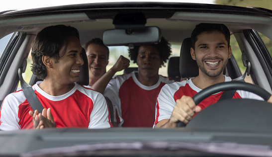 Happy group of Latin American soccer players driving to practice in a car and smiling - sports training concepts