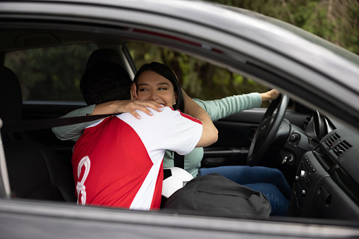 Soccer player wife saying goodbye to her husband after driving him to practice in her car