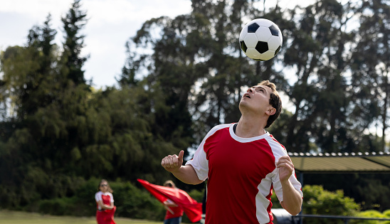 Portrait of a Latin American soccer player heading the ball at the field -  sports concepts