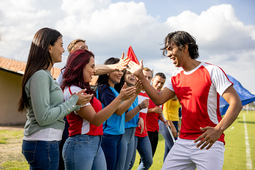 Happy Latin American soccer player greeting a group of excited fans at the sideline of the field - sports concepts