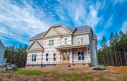 A family of four are standing outside of their new home. The sign in front of the house says, \