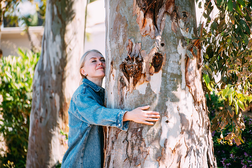 Charming Blonde Woman Hugging Old Tree Trunk