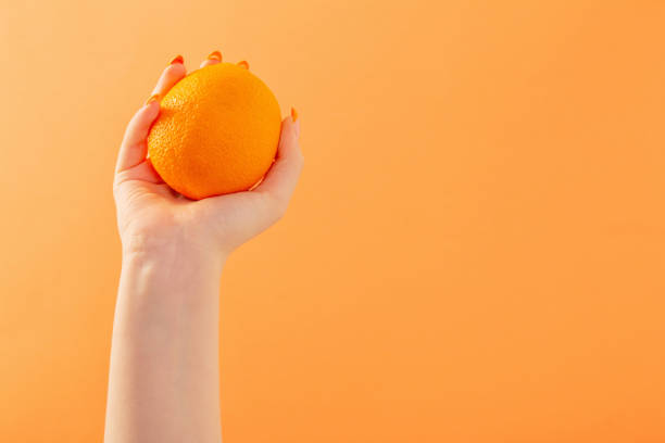 istock female hand with orange on orange background 1397940709