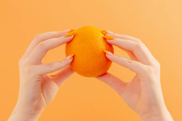 istock female hand with orange on orange background 1397940713