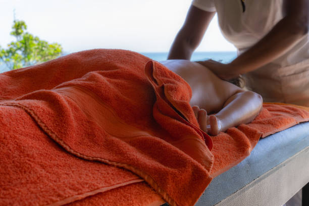 Relaxed woman lying down getting massage therapy in Caribbean beach spa stock photo