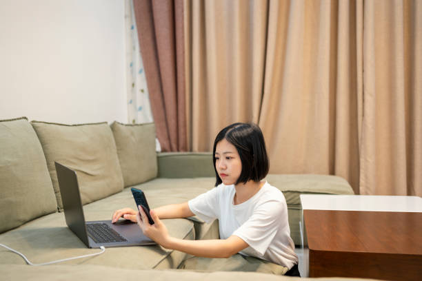 istock Asian woman using mobile phone while working at home with laptop at night 1397941018