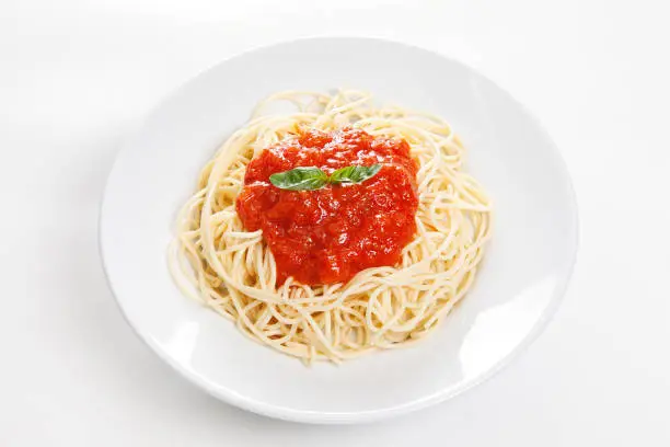 spagetthi with tomato sauce with green herbs in white plate